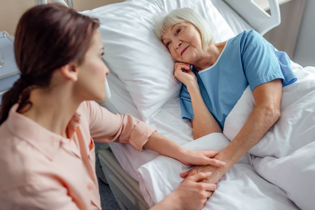 Hospice support caregiver holding hand of patient